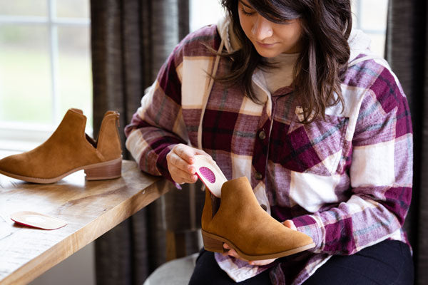 Woman placing heel cups inside suede boot