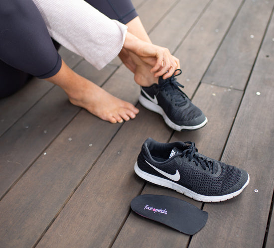 Woman placing ¾ orthotic insole into black tennis shoe