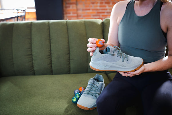 Woman placing shoe deodorizer in gray tennis shoe