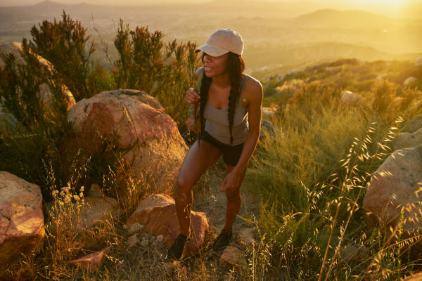 Woman hiking in summer wearing a tank top, shorts and a ball cap