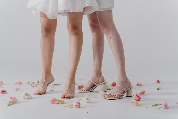 Two women wearing heeled sandals among flower petals
