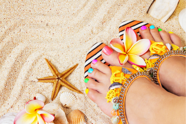 Woman’s feet in sandals showing a rainbow summer pedicure