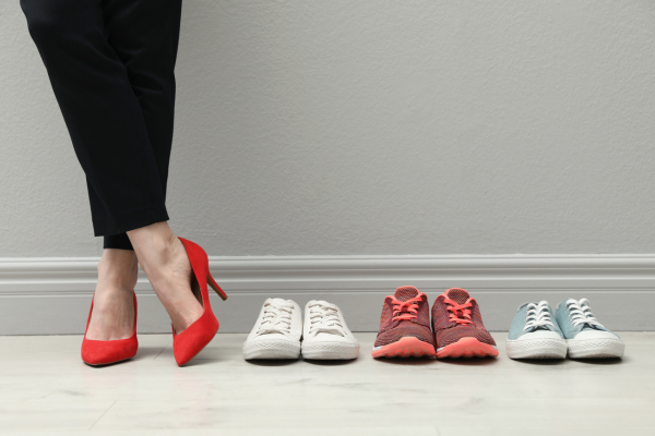 woman wearing red high heels next to three pairs of sneakers