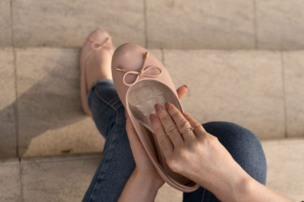 woman placing air gel ball of foot cushion into pink ballet flat