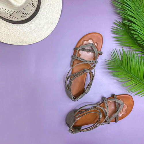 gray sandals with gel ball of foot cushions beside palm fronds and a sunhat