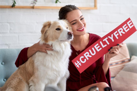 ragazza che abbraccia un cane e porta un cartello con scritta Cruelty Free