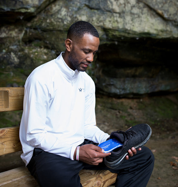 Man placing PowerStep bridge insoles into black shoe