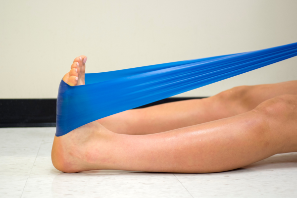 Person performing sitting calf stretch with blue exercise band
