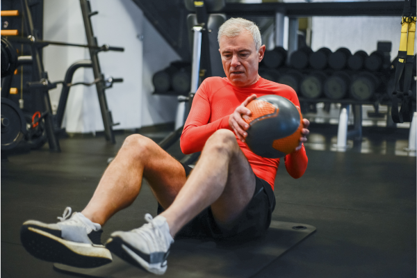 Man performing weighted exercises on mat on gym floor