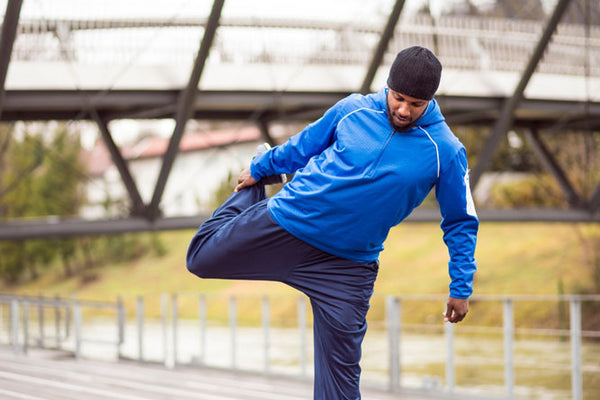 Man wearing athletic clothes stretching foot and leg