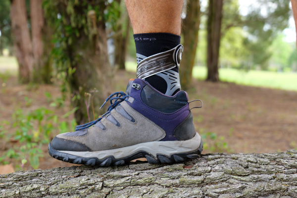 Person standing on log in hiking boot with Dynamic Ankle Support Sock