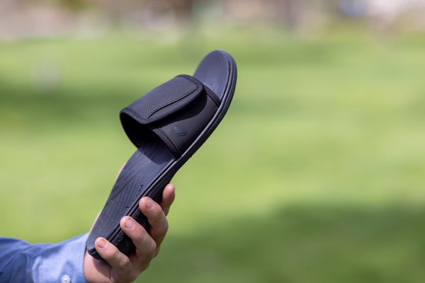 Person holding black PowerStep orthotic slide with arch support