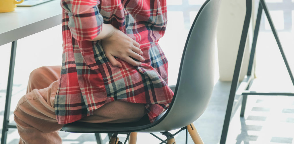 Man with lower back pain sitting in chair, can PowerStep orthotic insoles help with back pain?