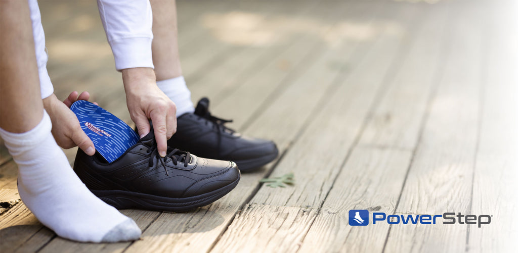 man placing insole in black orthopedic shoe