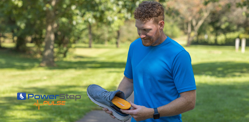 Man placing orange running insole into gray running shoe