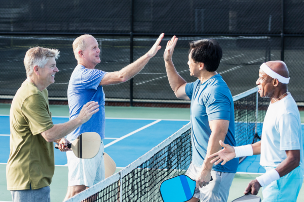 Group of elderly men high fiving while playing pickleball