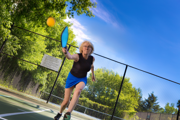 Woman lunging while playing pickleball outside