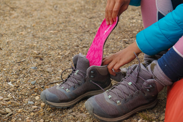 Woman putting pink shoe insole into hiking shoe