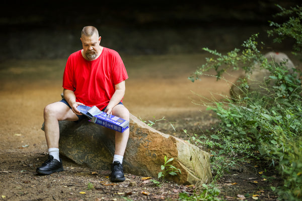 Man sitting on rock outside pulling blue insole out of box