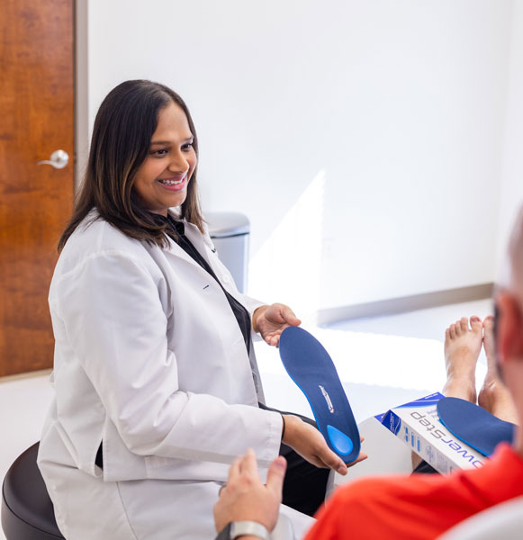 Female podiatrist talking to patient and holding an orthotic insole