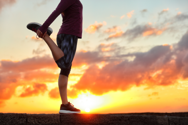 Person stretching leg outside at sunrise