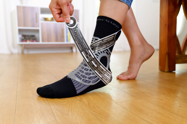 Person pulling on strap to put on dynamic ankle support sock