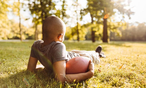 Boy holding football resting on the grass