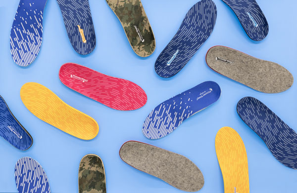 Various PowerStep insoles in blue, pink, yellow, camo, and gray