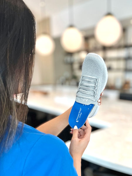 Woman placing blue shoe insole into gray shoe