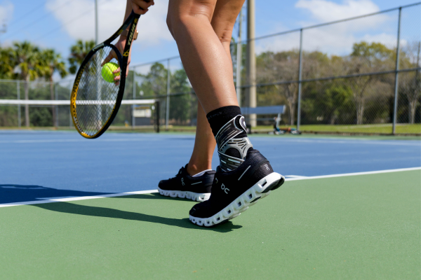 Woman playing tennis while wearing Dynamic Ankle Support Sock to prevent injury