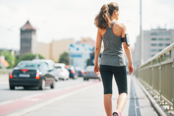 Woman taking a walking break while running on a bridge outside