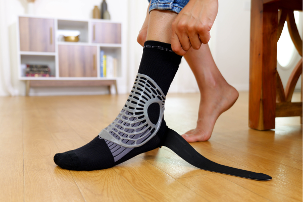 woman pulling on ankle brace sock over foot