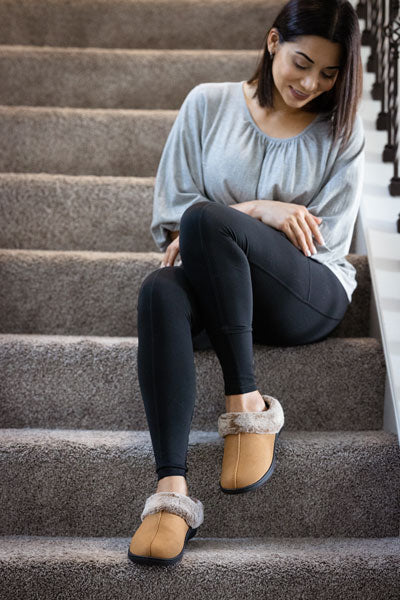 woman sitting on steps wearing brown orthotic slippers