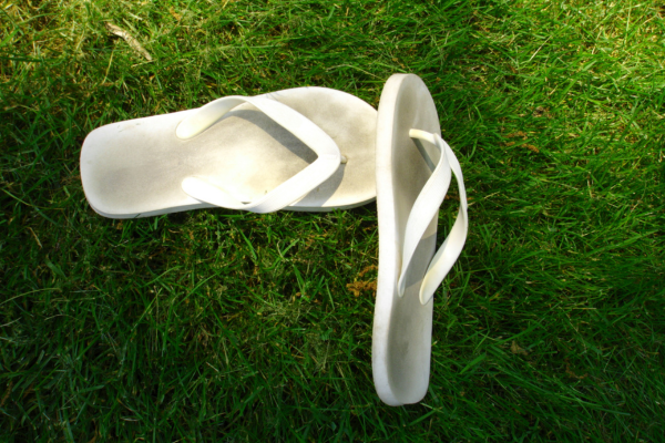 A pair of worn, white flip flops on the grass