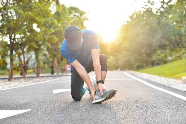 Male runner kneeling on road and holding heel in pain