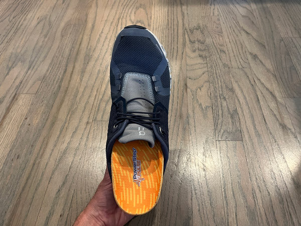 person holding running shoe with orange arch support running insole inside