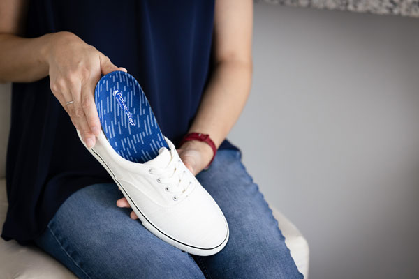 Person placing blue insole into white shoe