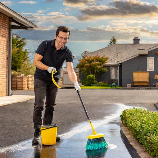 man using brush to clean driveway