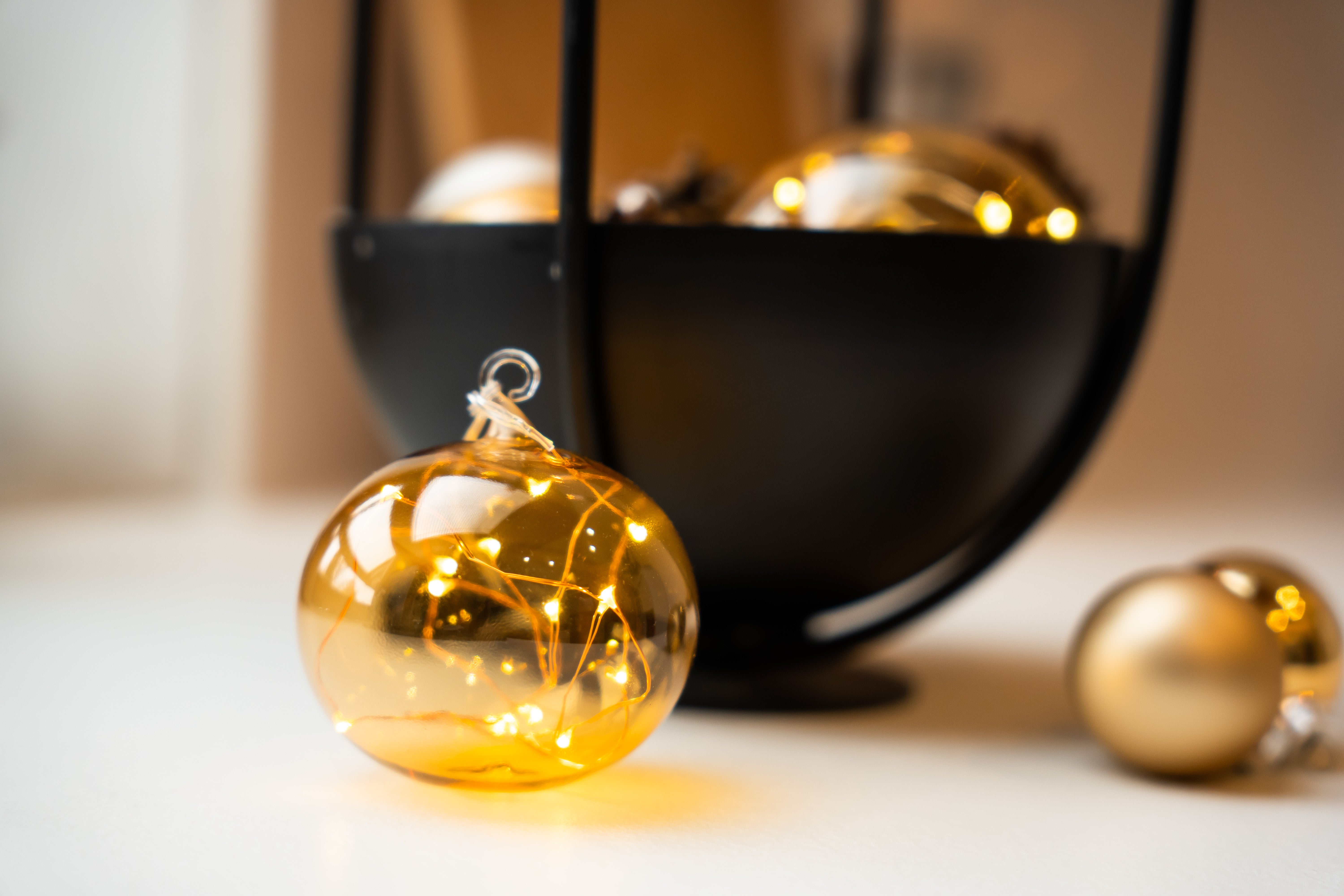 Lumix Light Balls Bernstein in einer schwarzen Schale mit Zapfen und Christbaumkugeln