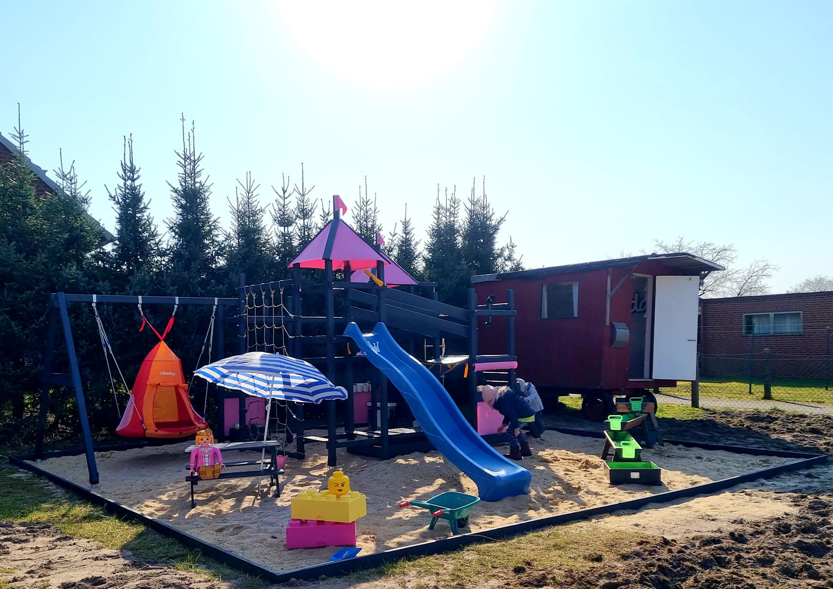 Spielhaus mit Rutsche, Klettergerüst und Schaukel für Kinder auf Krinner Bodendübel gebaut 