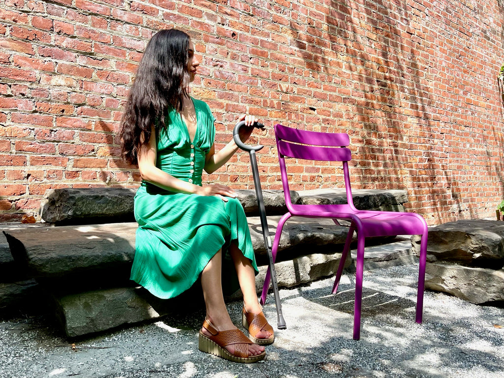 Marissa sitting in green dress with the black c-grip cane