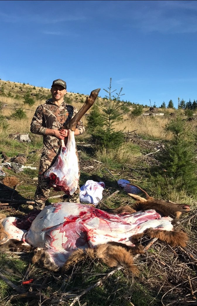 Lindon Loren lifts up an elk quarter after shooting a spike in an Oregon clearcut