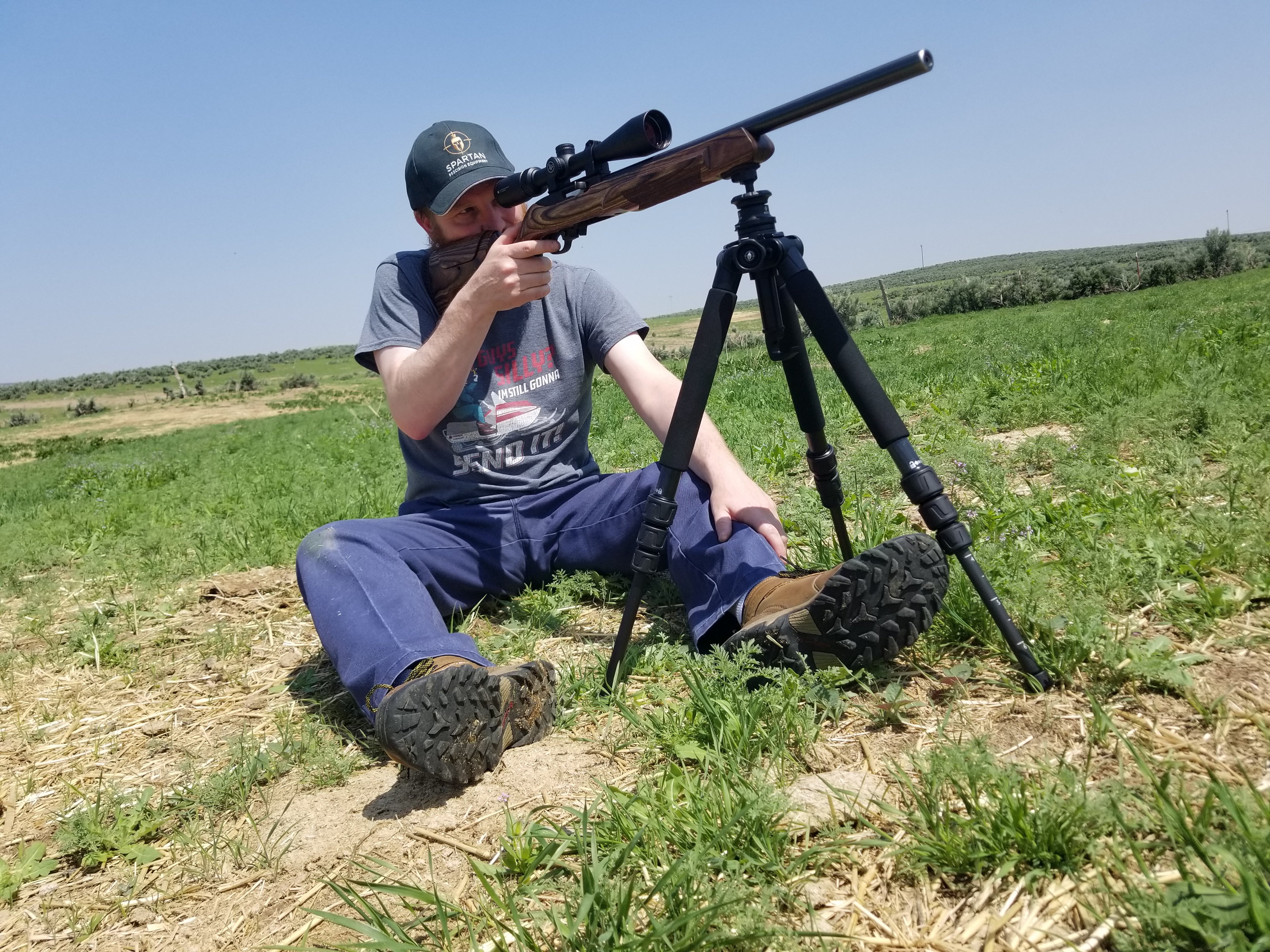 Shooter in a sitting position with the rifle mounted on an Ascent tripod