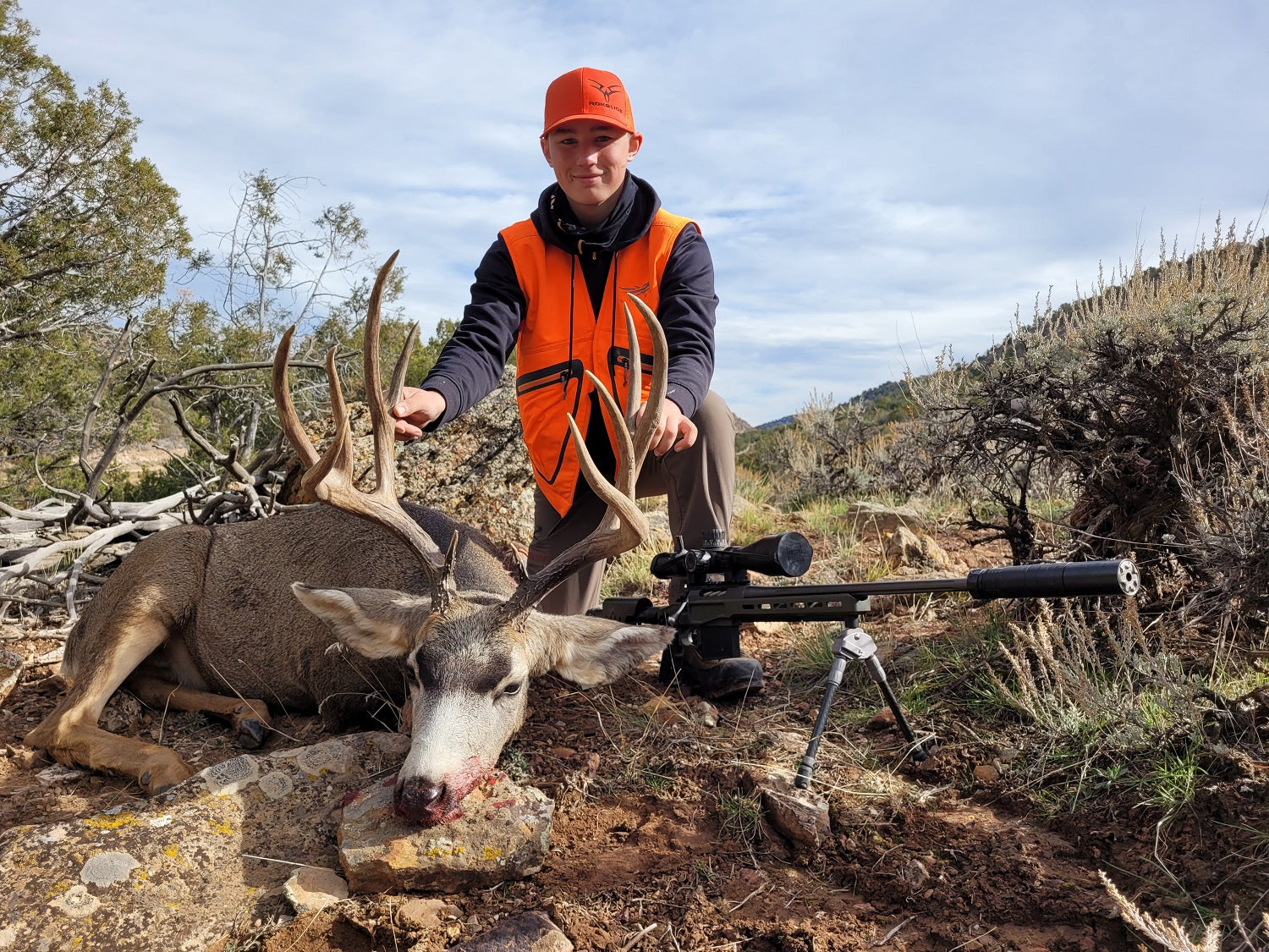 4 point mule deer buck held by the author’s son, next to his rifle with Javelin Pro Hunt bipod