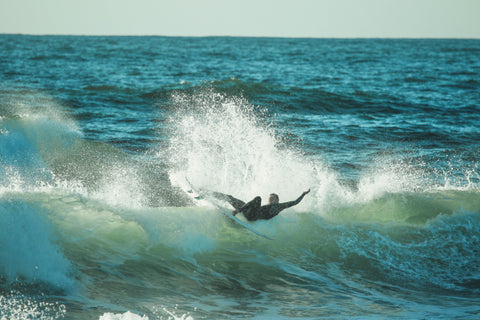 surfeur sur une vague en combinaison neoprene