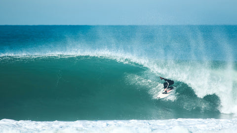 surfeur qui réalise un tube dans la vague.