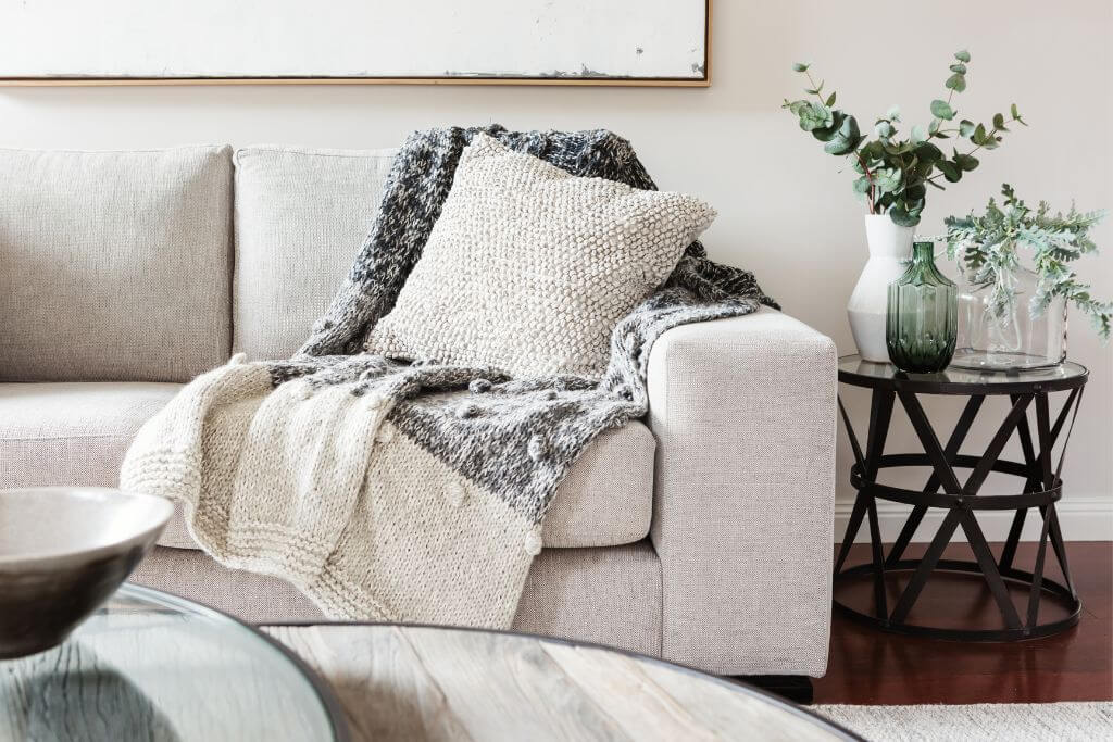 Grey couch with grey blanket on it
