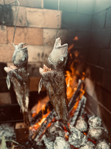 Whole fish cooked hanging over fire.