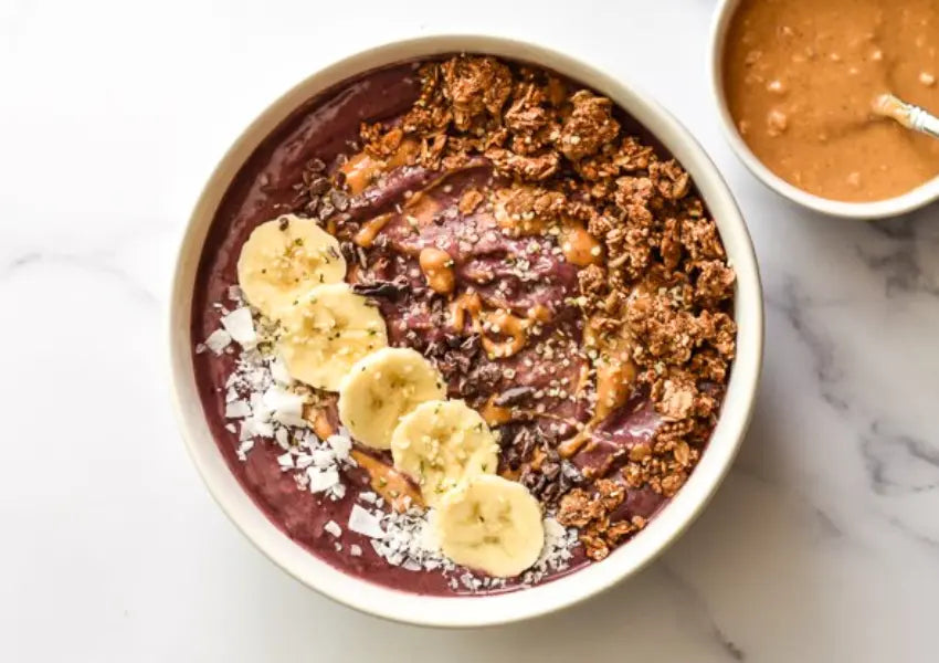 acai bowl with sliced bananas, shredded coconut flakes, and drizzled with peanut butter