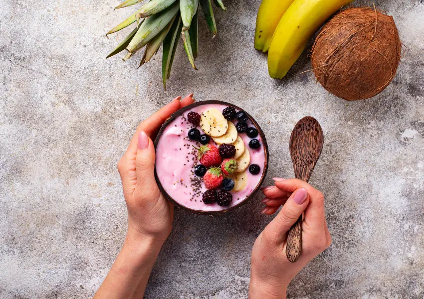 woman holding smoothie superfood bowl topped with chia, bananas, strawberries and blueberries